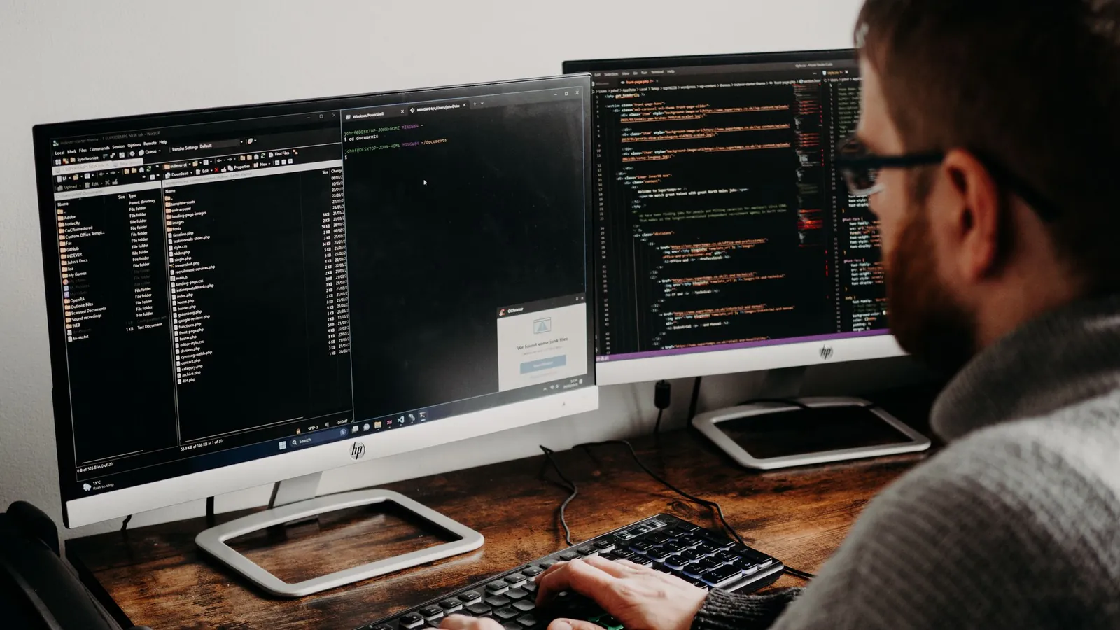 Developer working on code across two monitors while fixing items on a technical SEO checklist