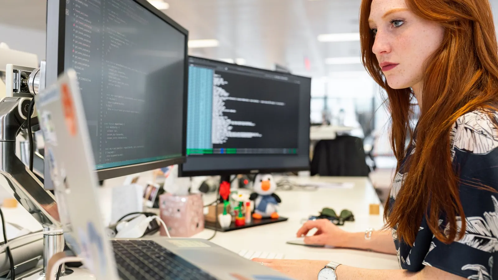 Software engineer coding at dual monitors, implementing technical SEO fixes