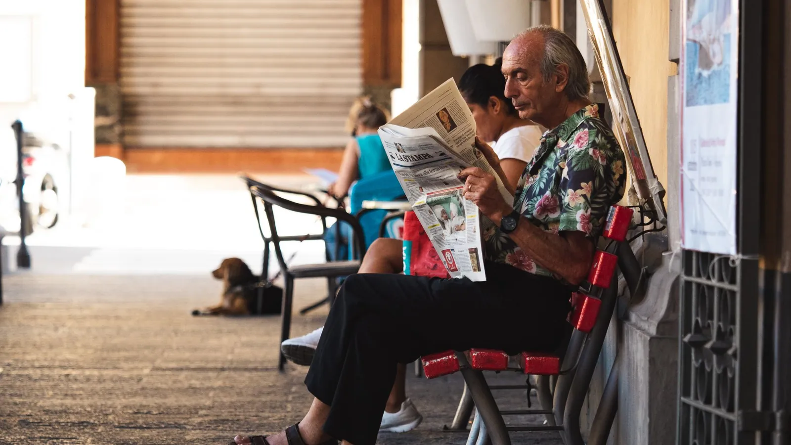 Man reading a newspaper at a cafe, one of the traditional marketing channels still used today